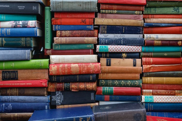 Photograph of vertical piles of used books of different shapes, sizes, and colours.