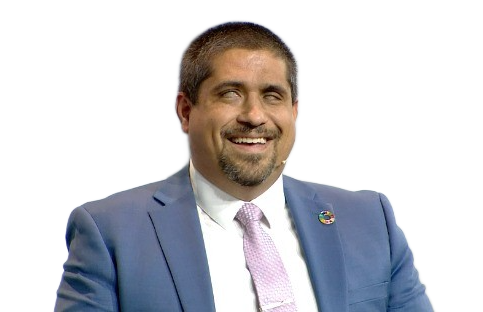 Picture of a man with a joyful smile. Jose is blind, has light brown skin, an elegant blue suit, short dark hair and goatee.
